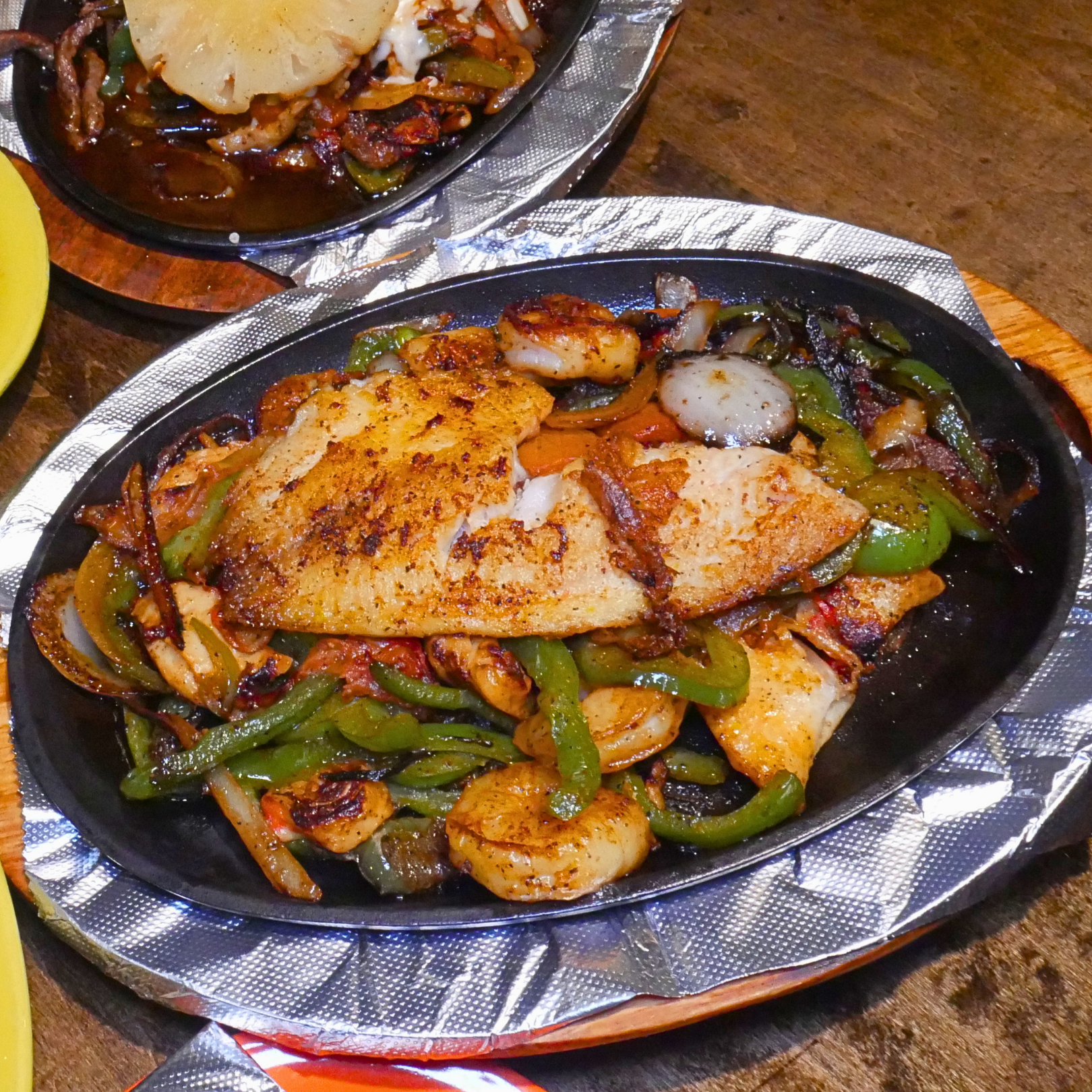 Sizzling seafood fajitas with crabmeat, tilapia, shrimp, peppers, onions, tomatoes, rice, beans, tortillas.