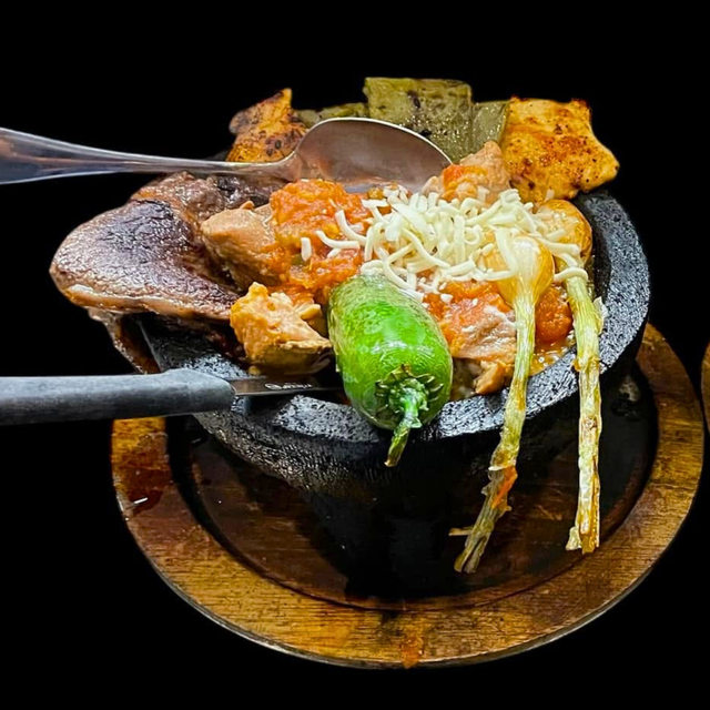 Molcajete with grilled chicken, steak, shrimp, chorizo, cactus, fried jalapeño, cheese, rice, beans, tortillas.