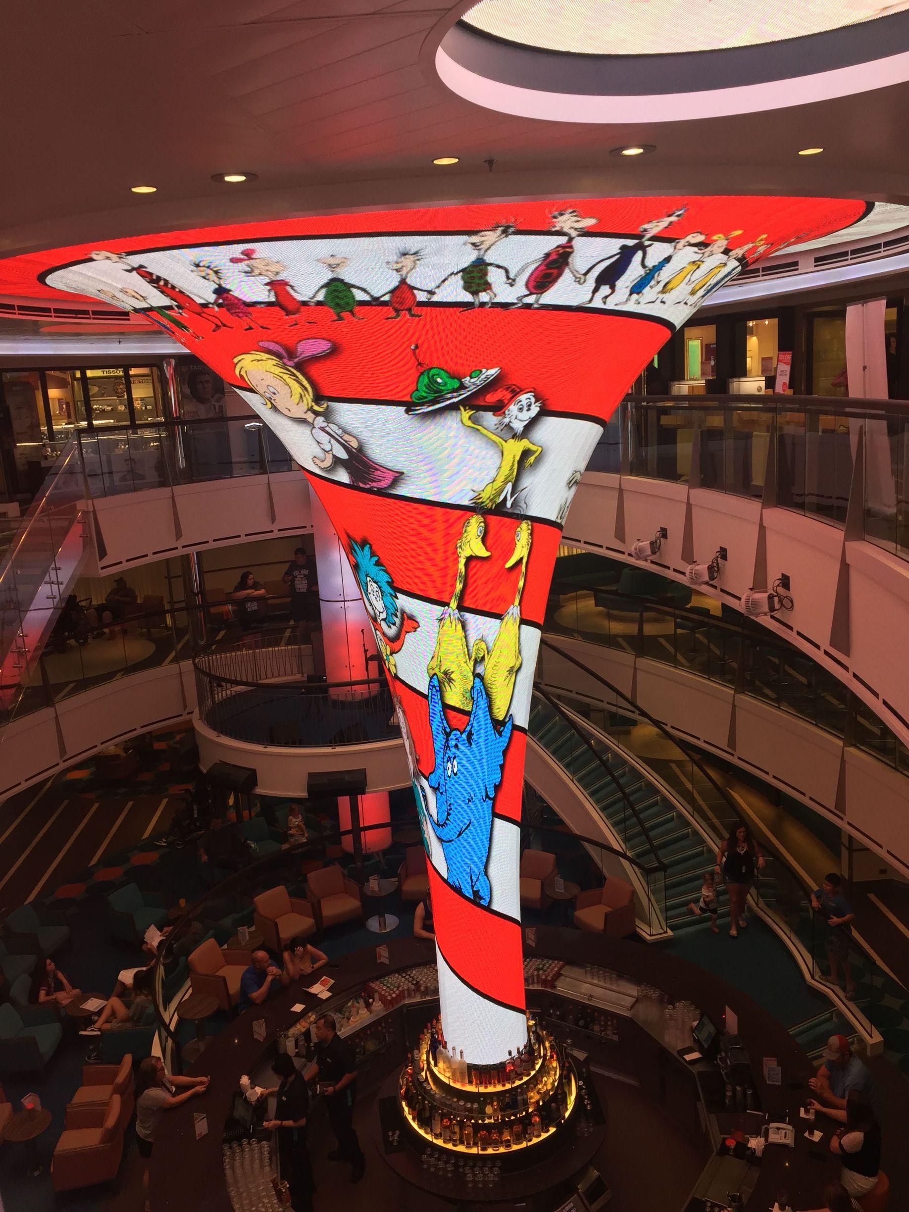 Colorful spiral chandelier sculpture in a circular lobby with people seated below