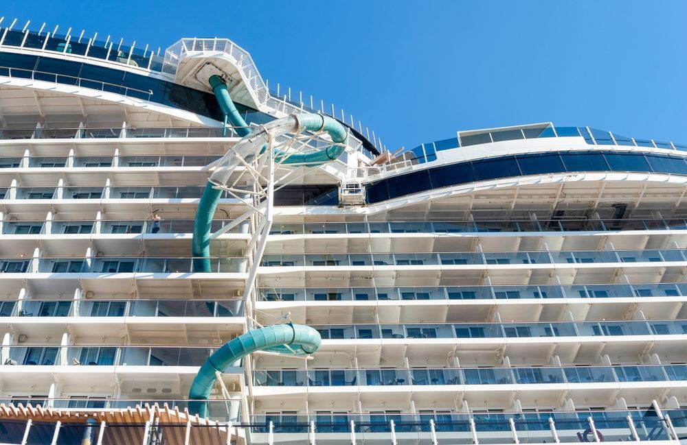 Modern cruise ship with stacked balconies and a twisting turquoise water slide