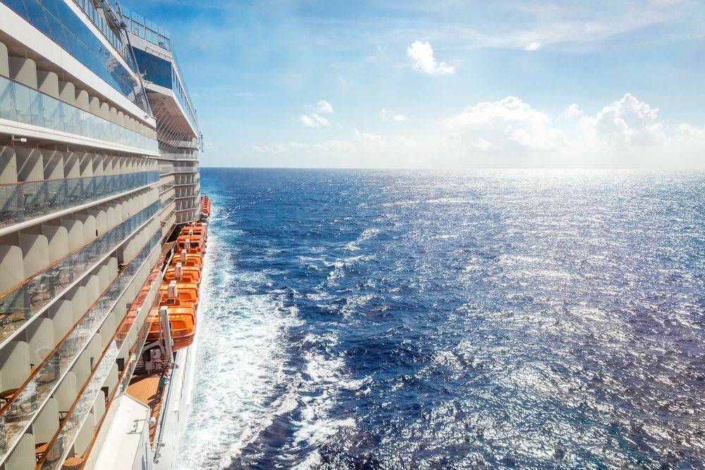 Cruise ship deck beside a sparkling blue ocean under a bright sky