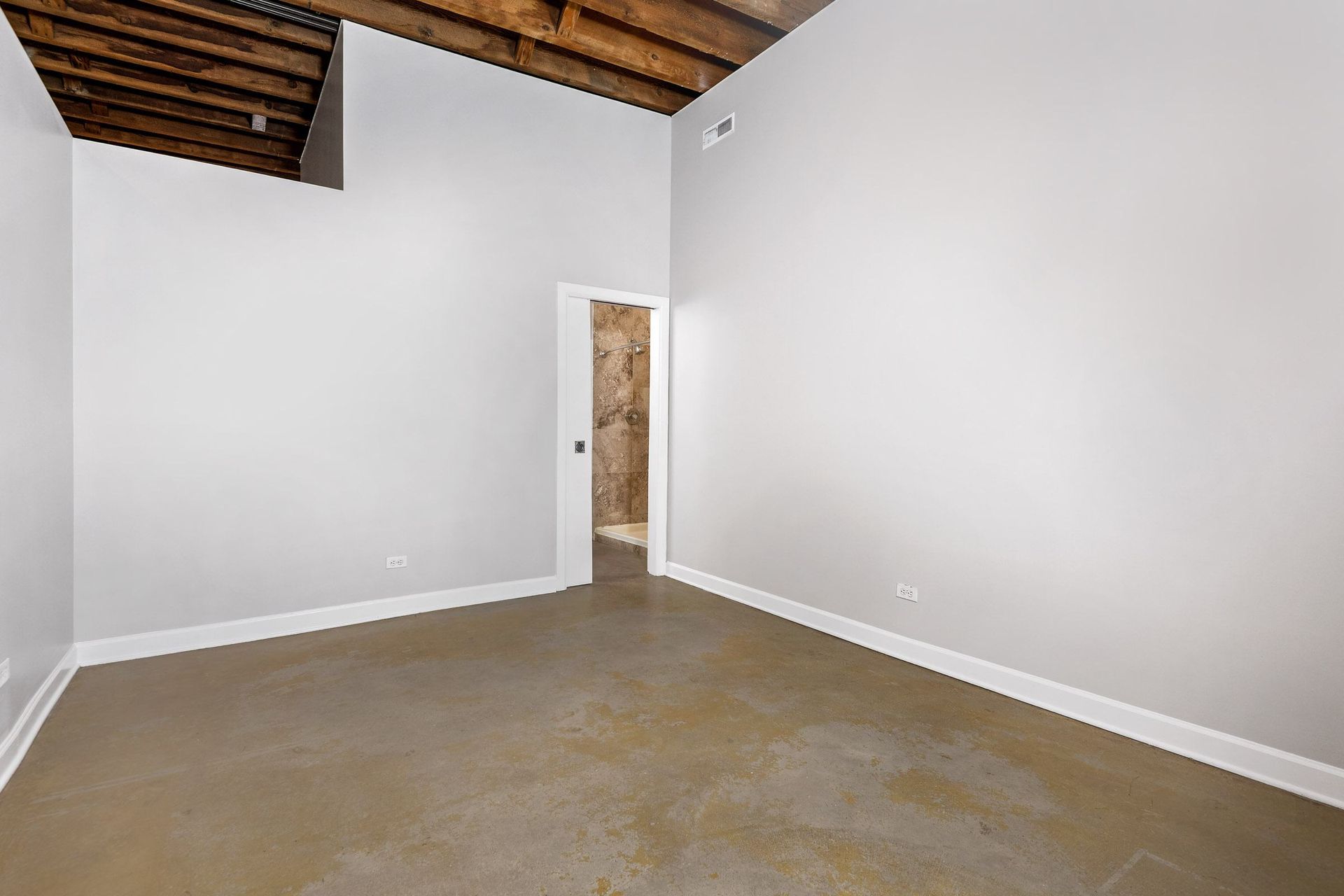 an empty room with white walls and a cement floor