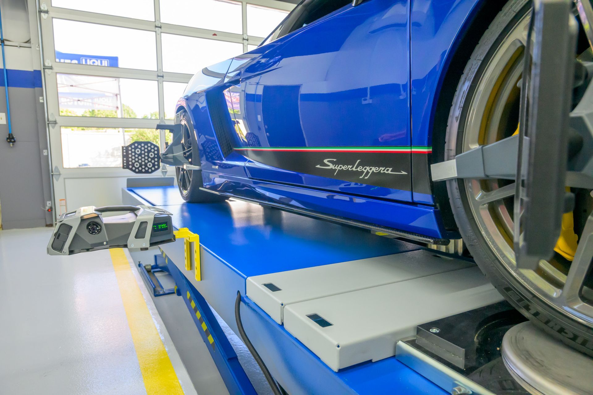 Blue sports car on a lift for wheel alignment check | Plum Springs Garage