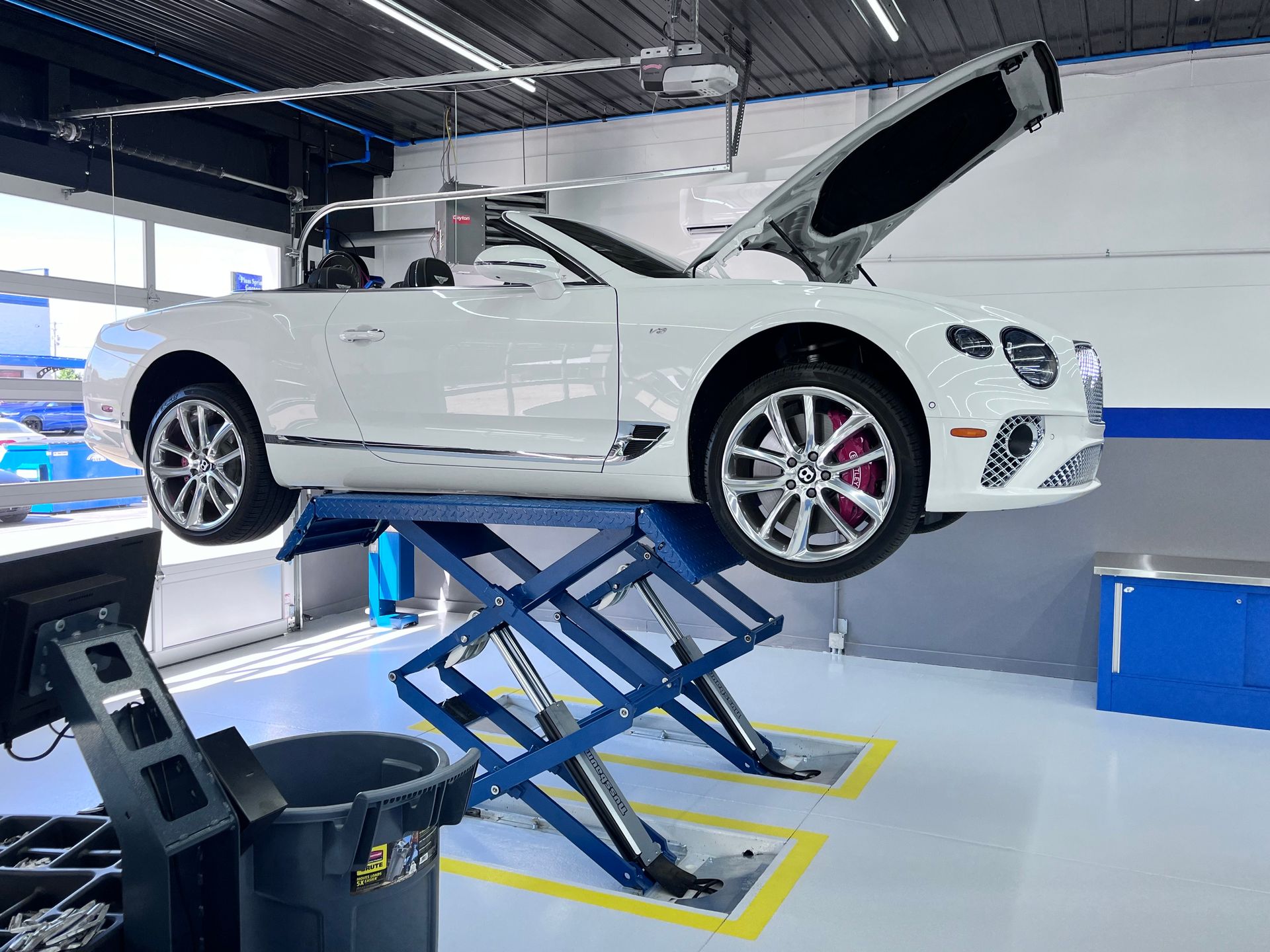White Bentley convertible on a blue scissor lift | Plum Springs Garage