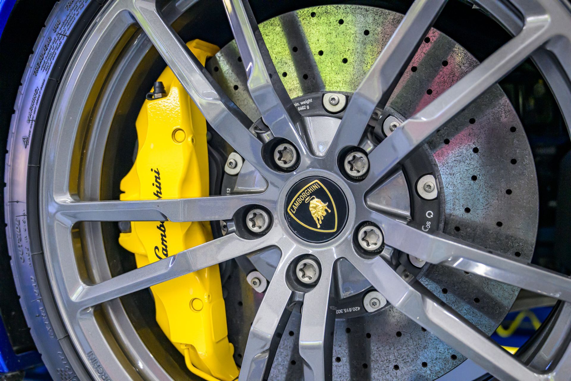 Yellow Lamborghini brake caliper behind gray wheel | Plum Springs Garage