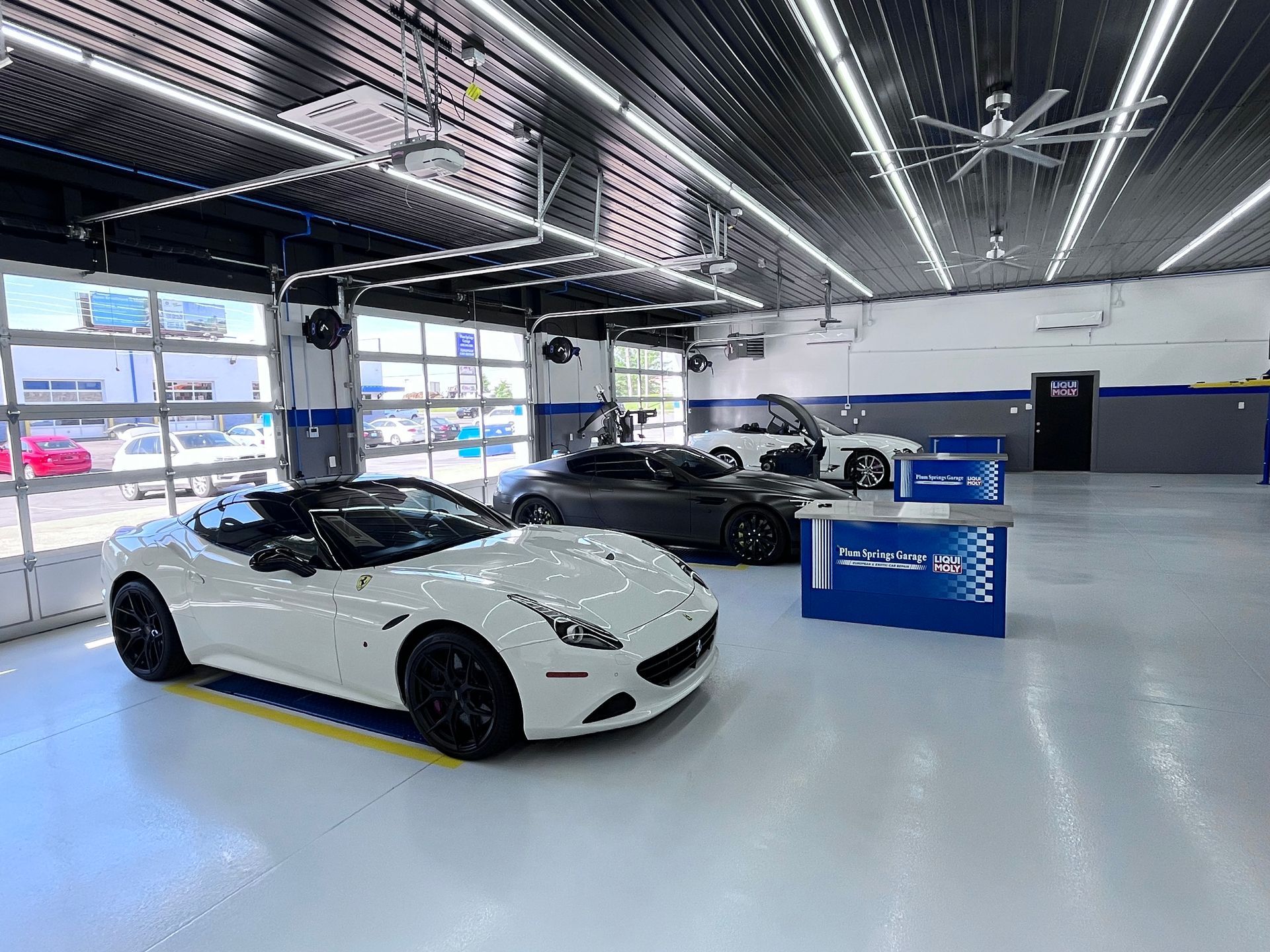 White convertible and other cars inside the auto shop | Plum Springs Garage