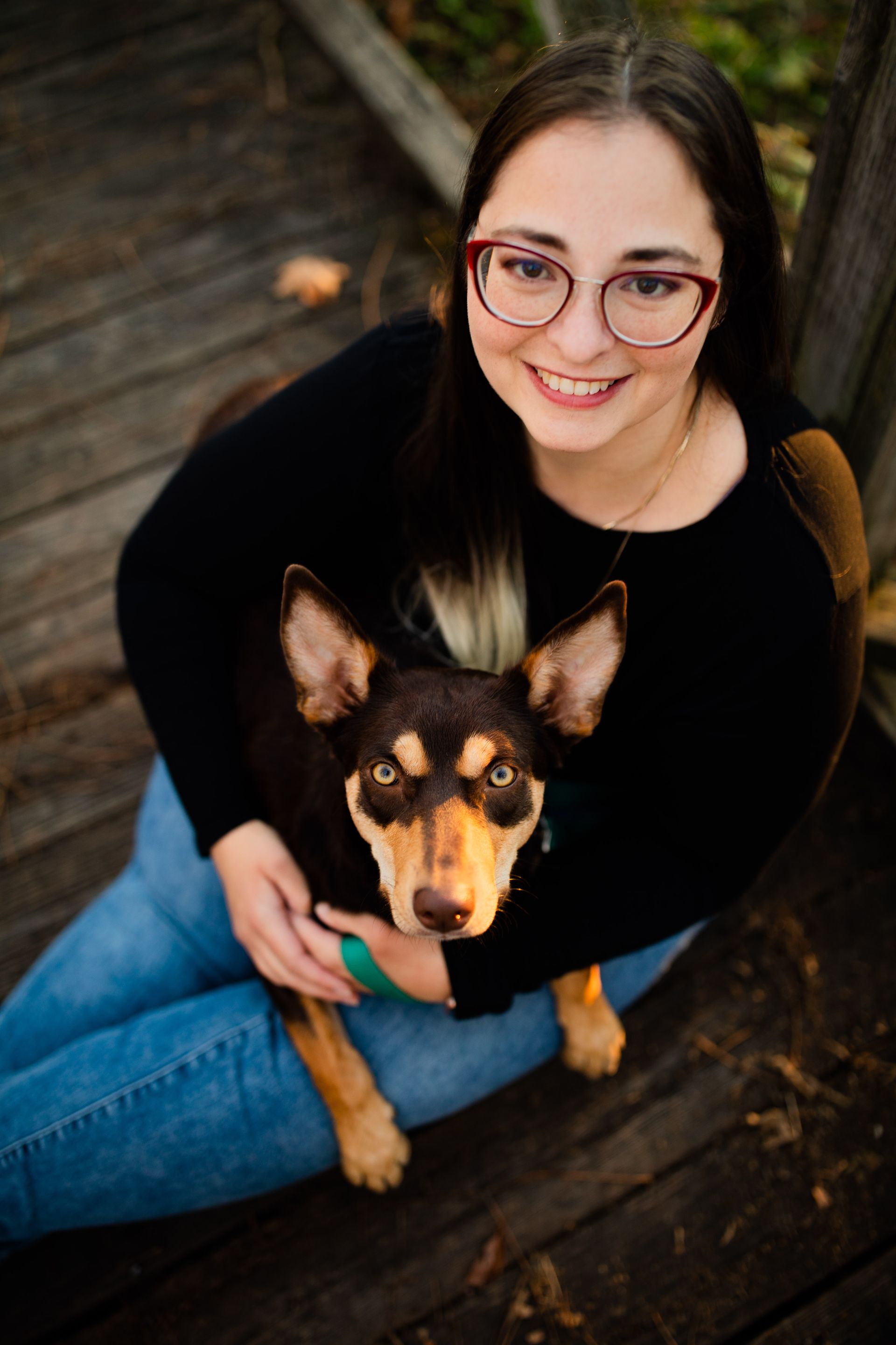 Dr. Jessi Turner is sitting on the floor holding a dog .