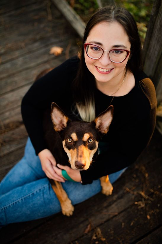 Dr. Jessi Turner is sitting on the floor holding a dog .