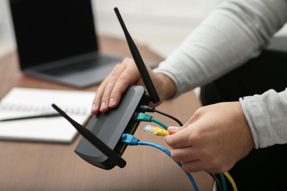 A person is plugging wires into a router.