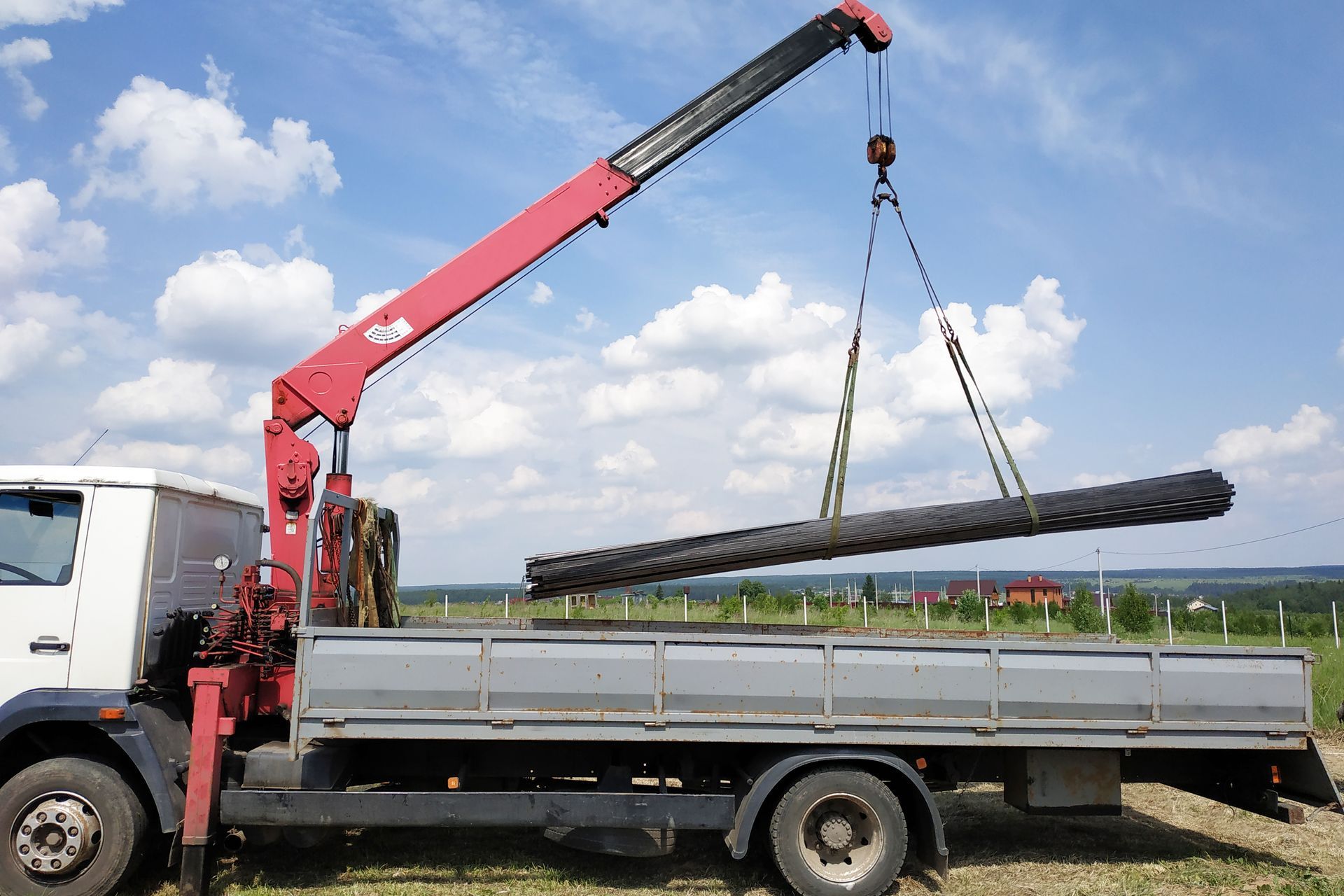 A crane is lifting a large piece of metal from the back of a truck.