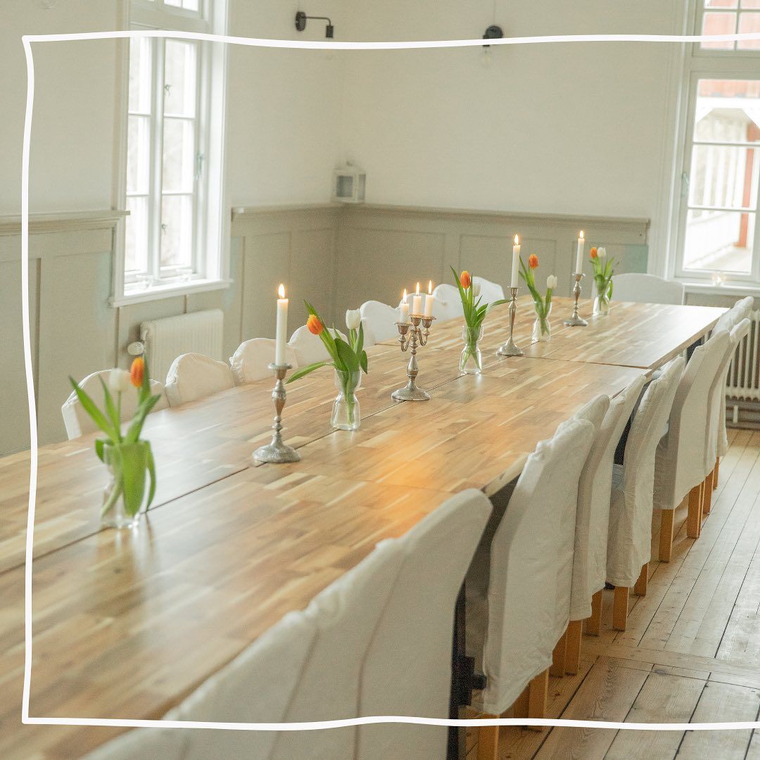 A long wooden table with candles and vases of flowers on it