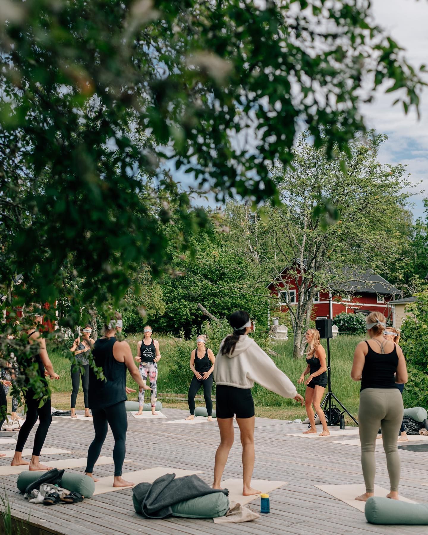 A group of women are standing on yoga mats in a park.