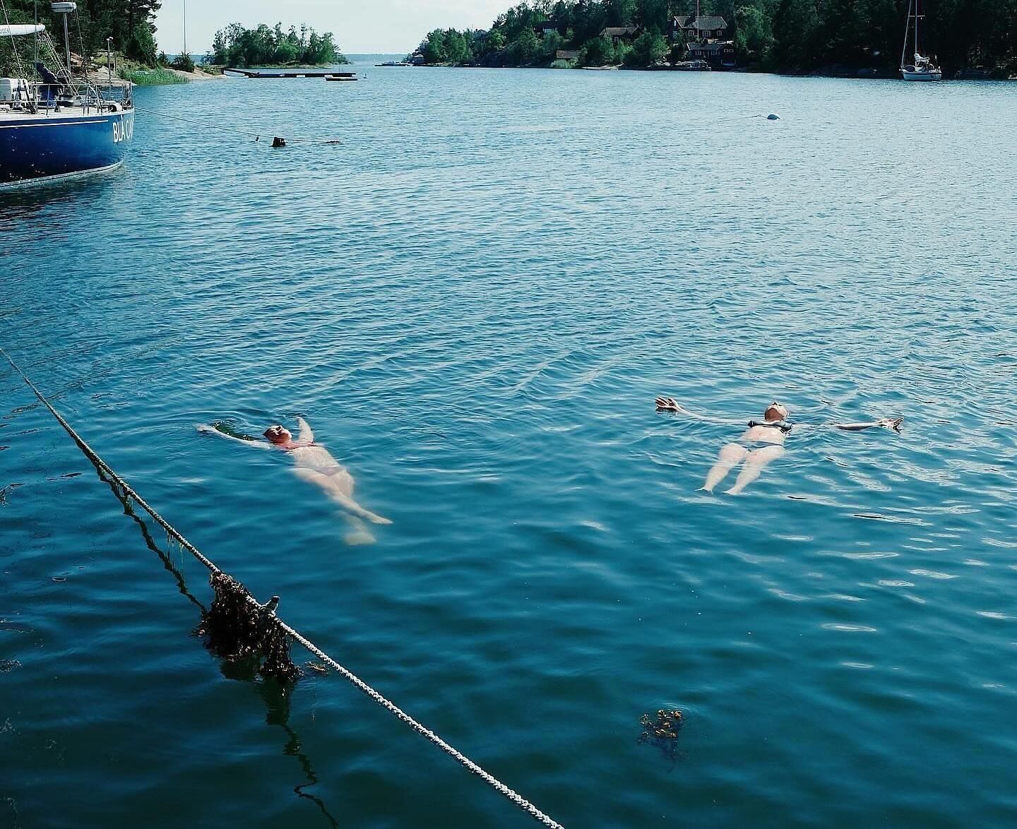 Two people are swimming in the water near a boat