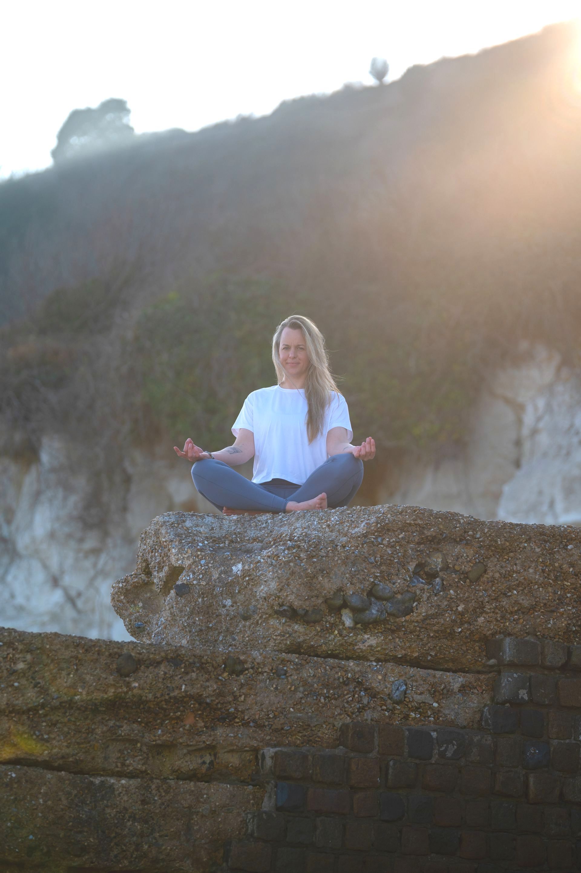 A woman in a green top and white pants is smiling