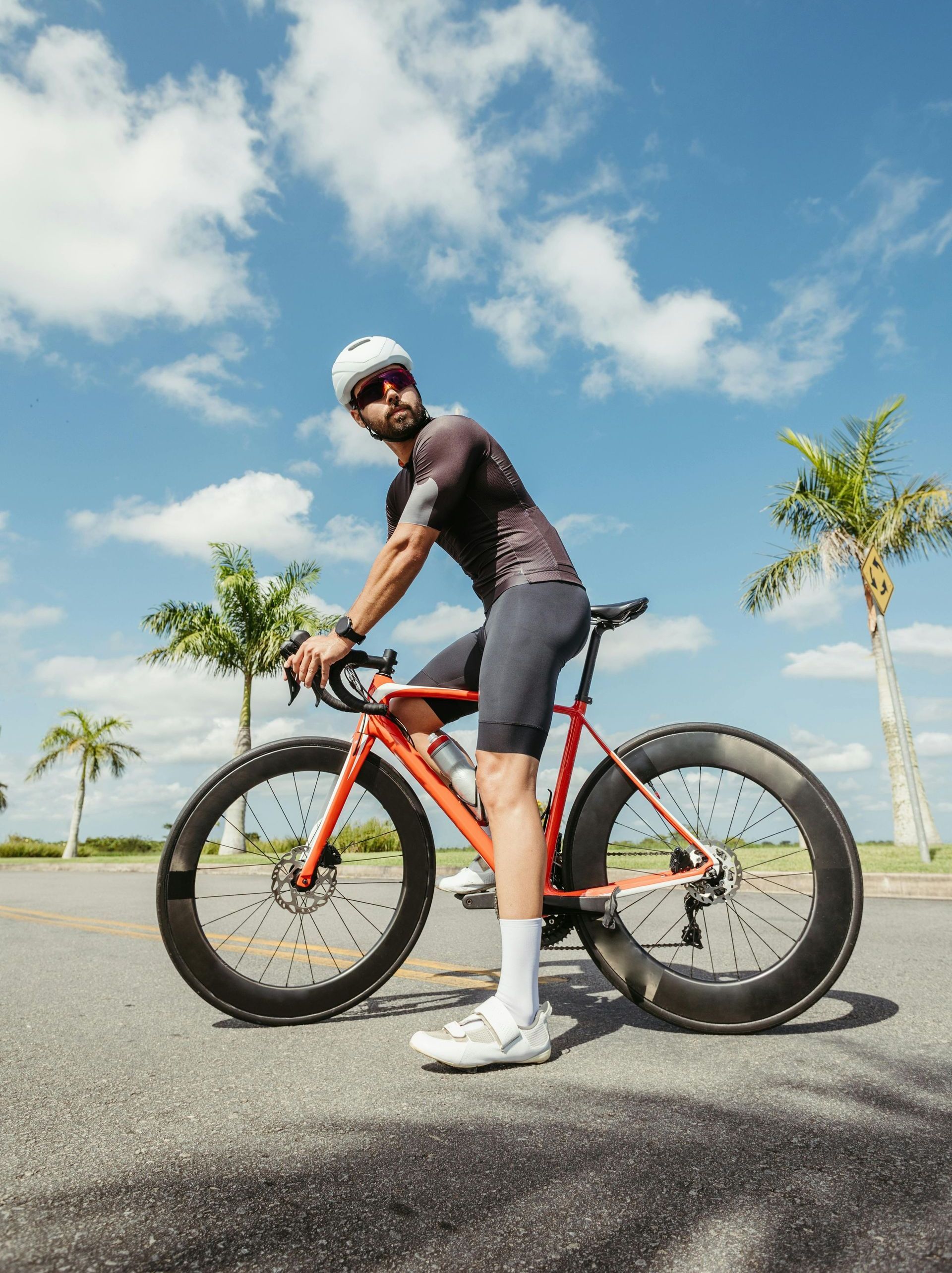 A man is standing next to a bicycle on the side of the road.