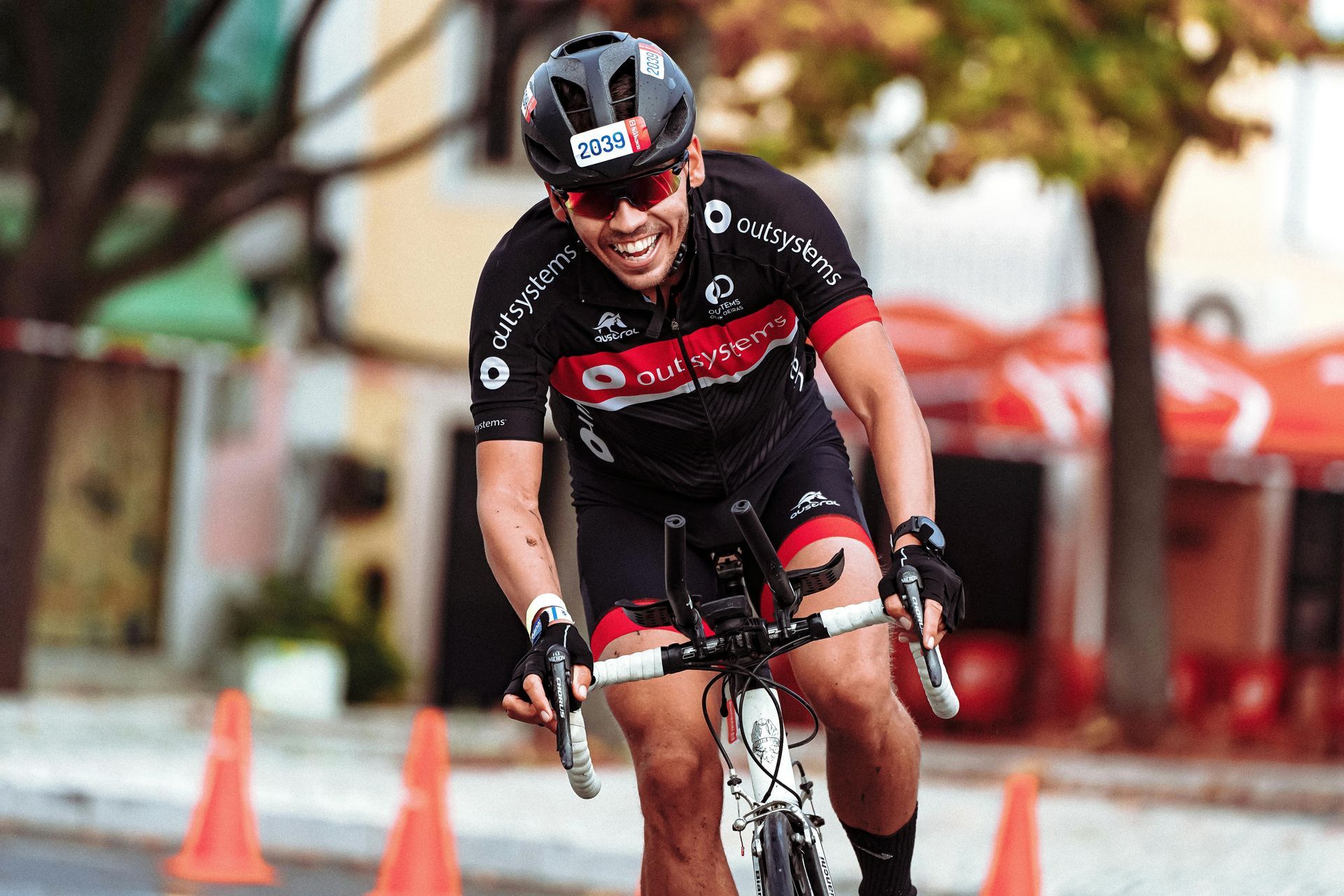 A man wearing a helmet and sunglasses is riding a bike down a street.