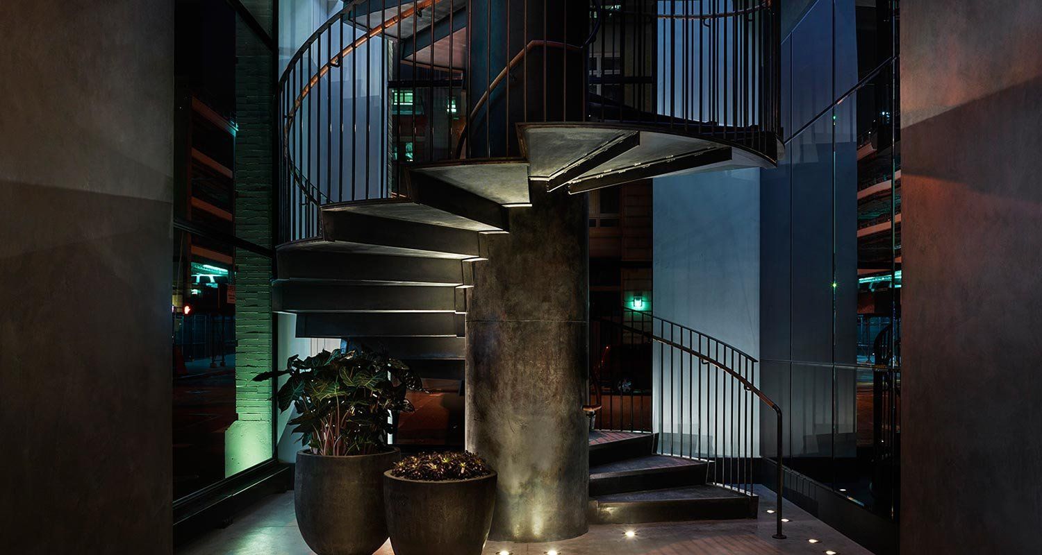 a spiral staircase with plants and modern lighting