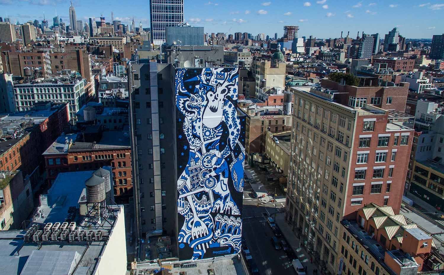 City skyline with a tall building covered in blue-and-white mural art.