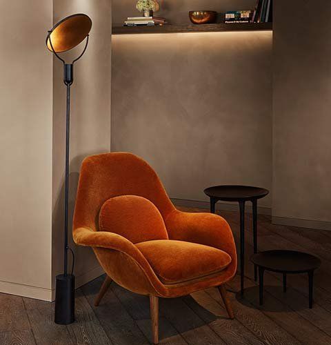 Orange armchair with floor lamp and small tables in a cozy, modern corner nook