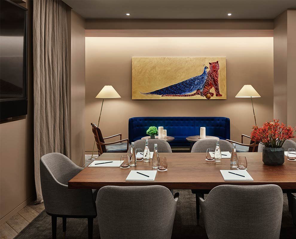 Elegant dining room with a set table, gray chairs, warm lamps, and abstract wall art.