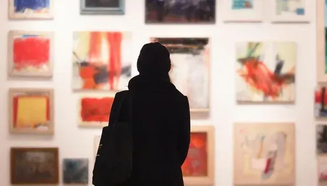 Person standing before a wall of colorful abstract artwork in a gallery