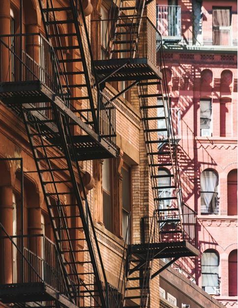 Row of urban fire escapes on brick apartment buildings in warm sunlight