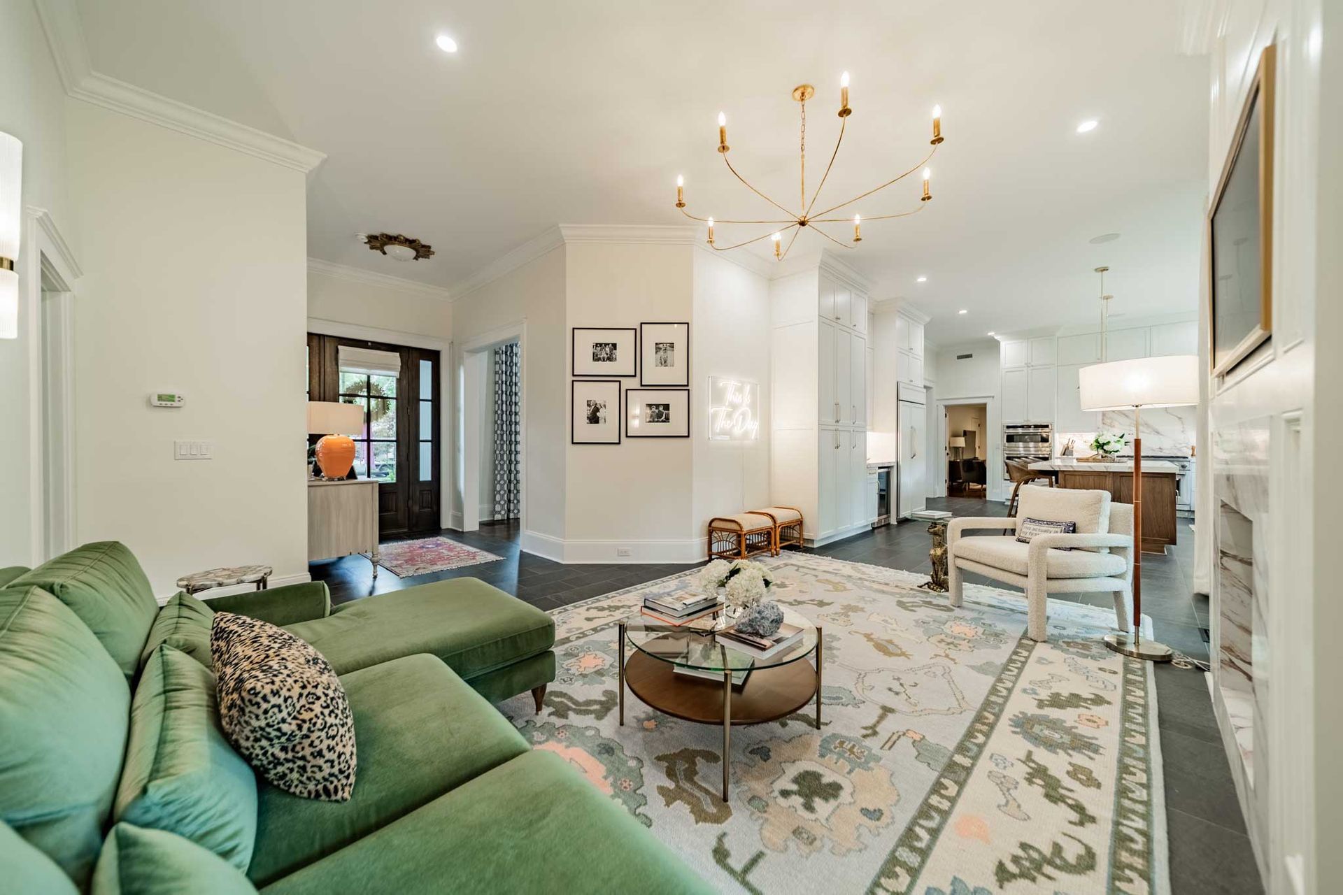 A living room with a green couch , chairs , a coffee table and a chandelier.
