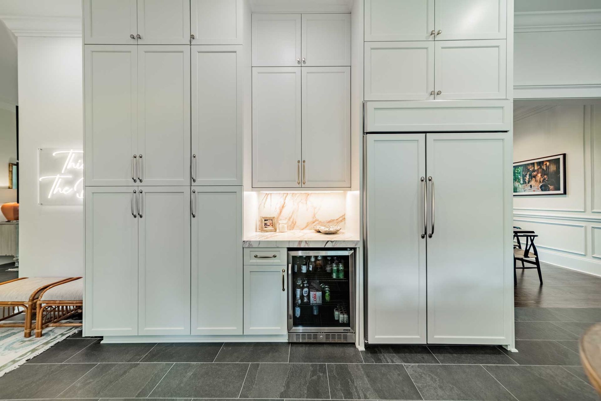 A kitchen with white cabinets , a refrigerator and a wine cooler.