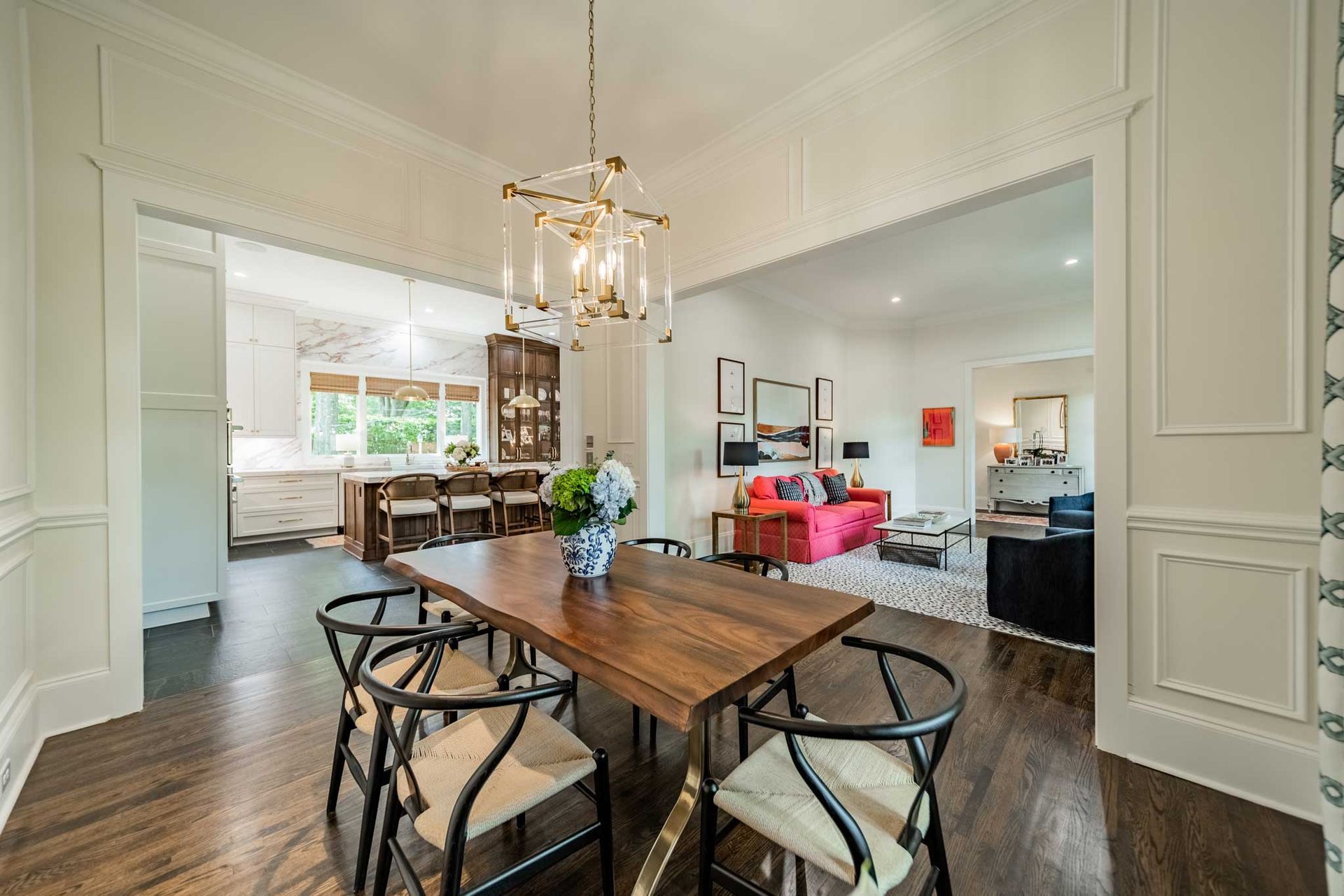 A dining room with a wooden table and chairs and a chandelier.