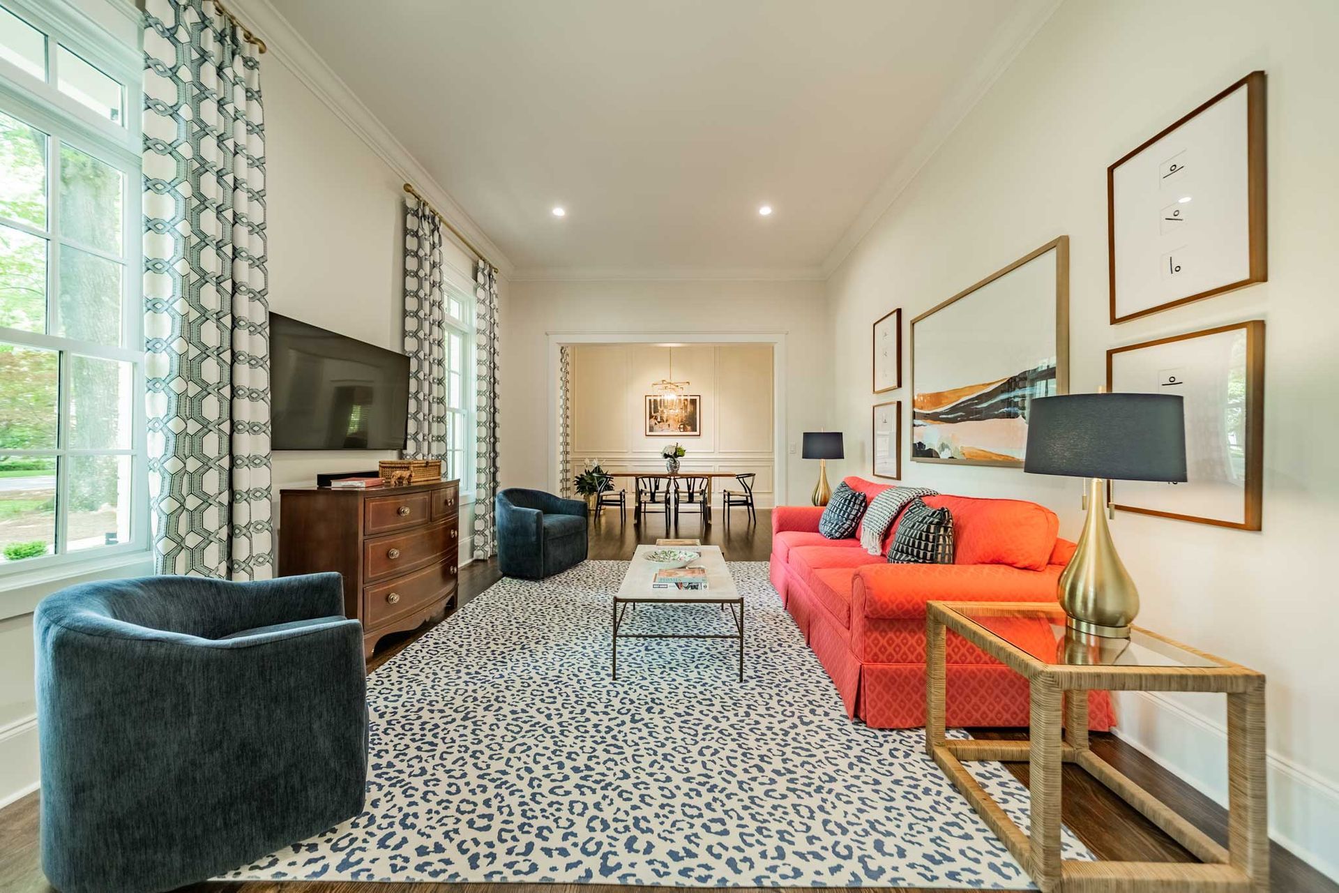 A living room with a red couch , two chairs , a coffee table , and a television.