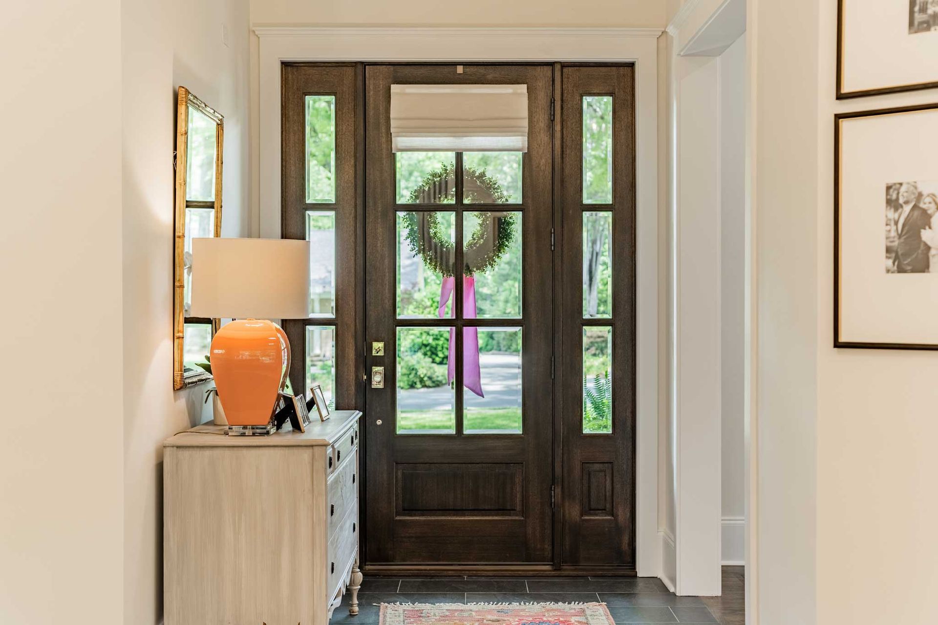 A hallway with a large wooden door and a lamp.