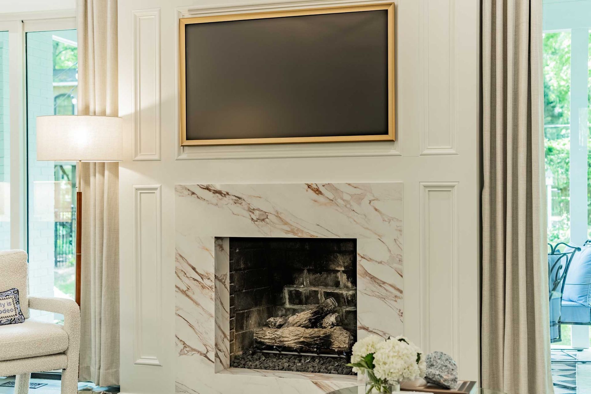 A living room with a fireplace and a flat screen tv on the wall.
