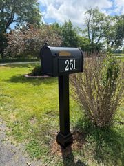 Brick mailbox pillar with brown mail slot and house number 2687 on a lawn near a road.