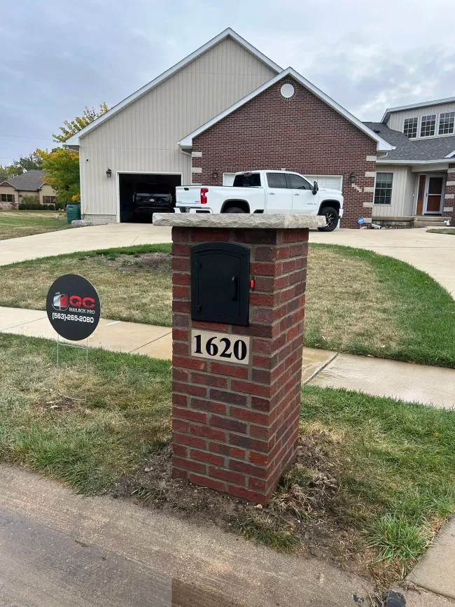 Brick mailbox post with house number 1620 in front of a suburban home and driveway.