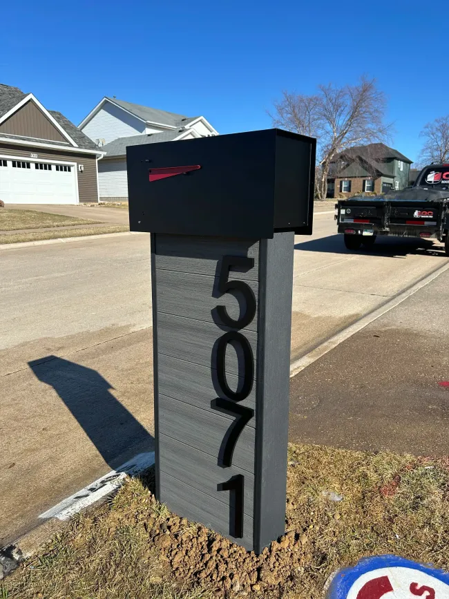 Black mailbox on gray stone post with house number 1601 on a suburban street