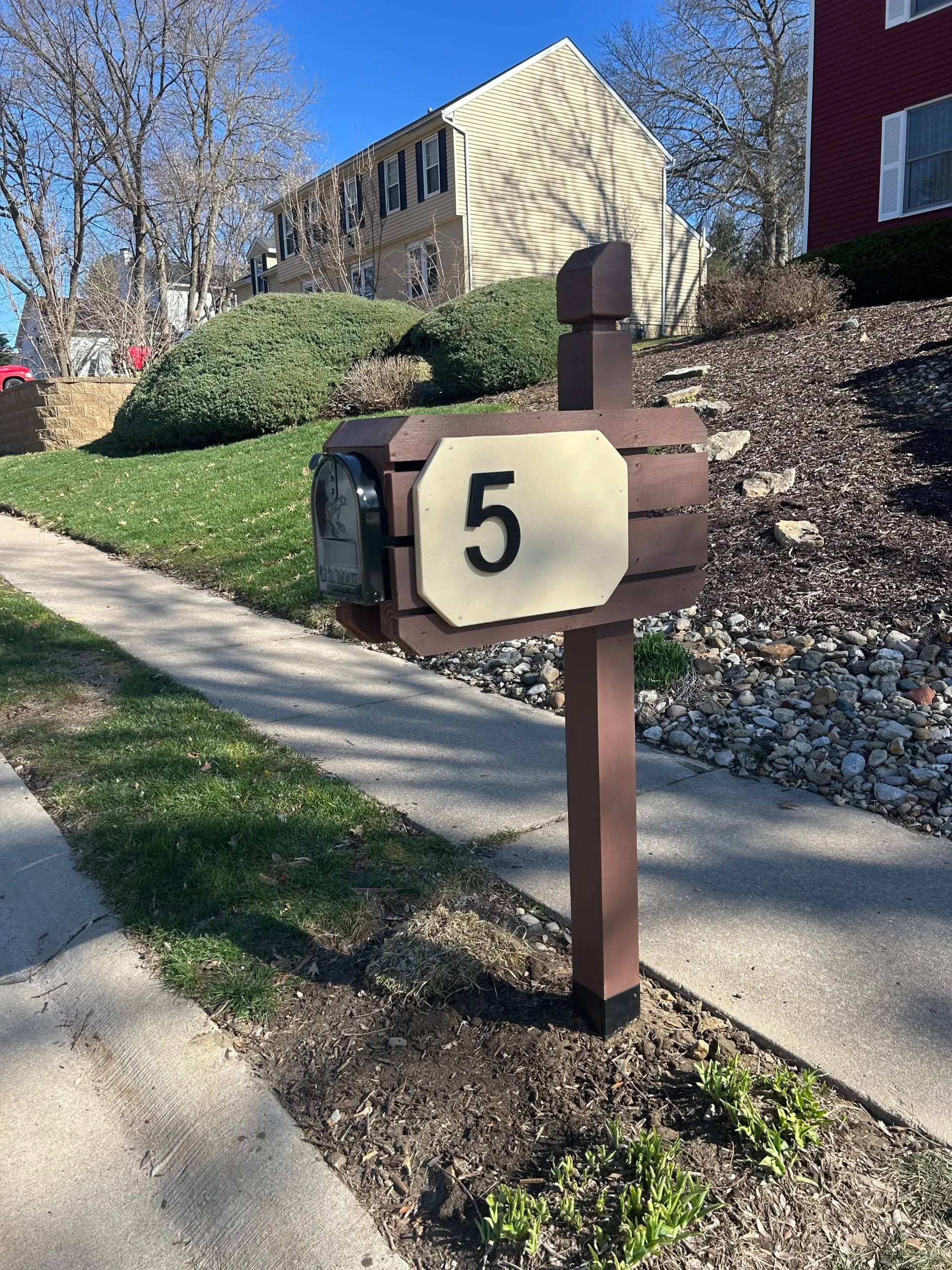 Mailbox labeled “5” beside a sidewalk in a landscaped apartment complex