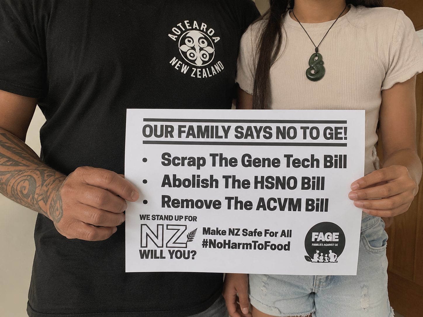 Dad and child holding a sign reading “Our Family Says No to GE.  Scrap The Gene Tech Bill. Abolish The HSNO Bill Remove. The ACVM Bill