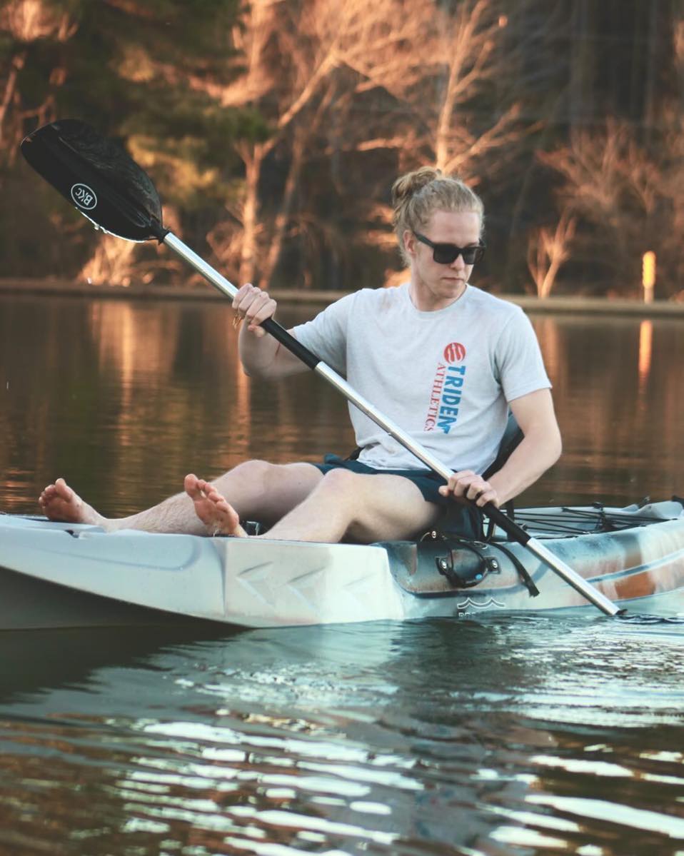 A woman is sitting in a kayak on a lake holding a paddle.
