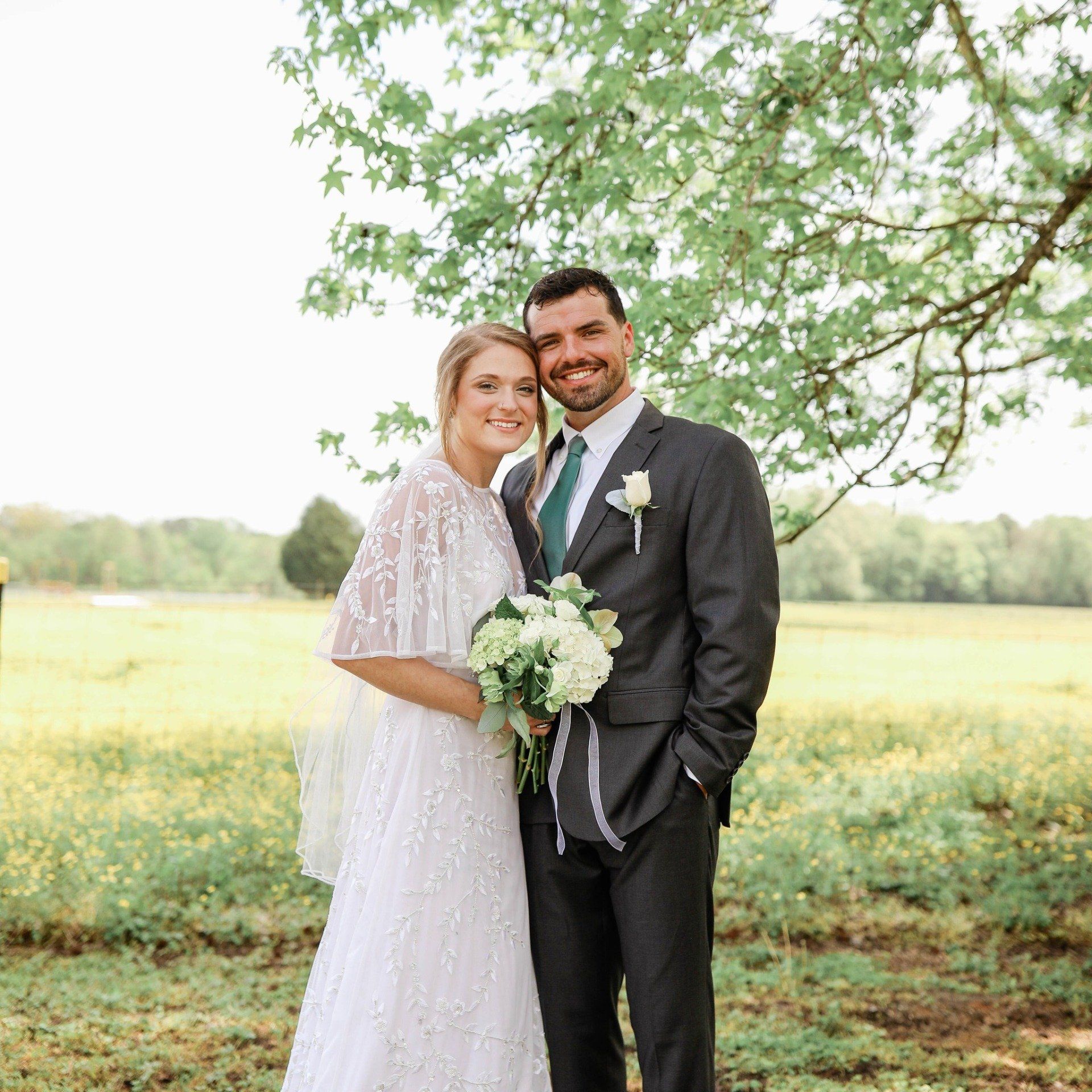 A bride and groom are posing for a picture in a field.