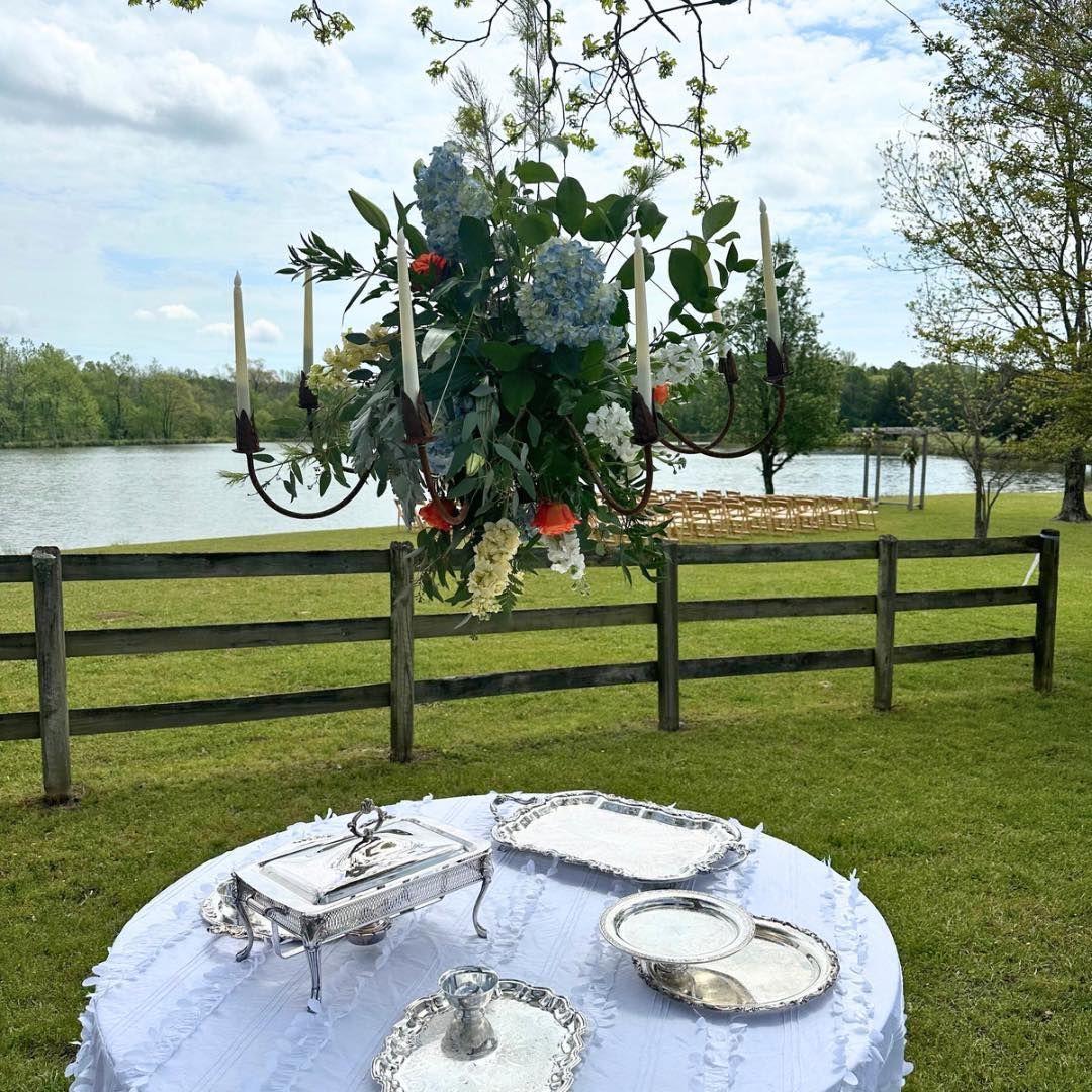 A table with plates and candles on it in front of a lake.
