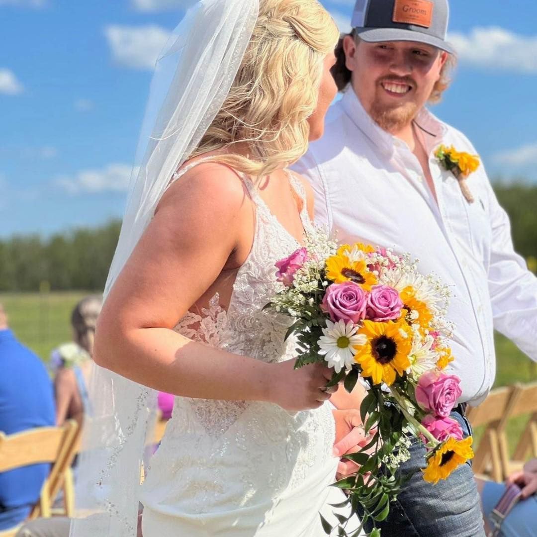 A bride and groom are posing for a picture while the bride is holding a bouquet of flowers