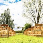A row of wooden folding chairs are lined up in a grassy field.