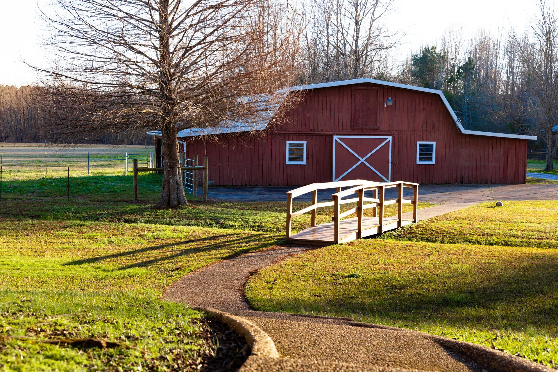 A red barn with a wooden bridge in front of it