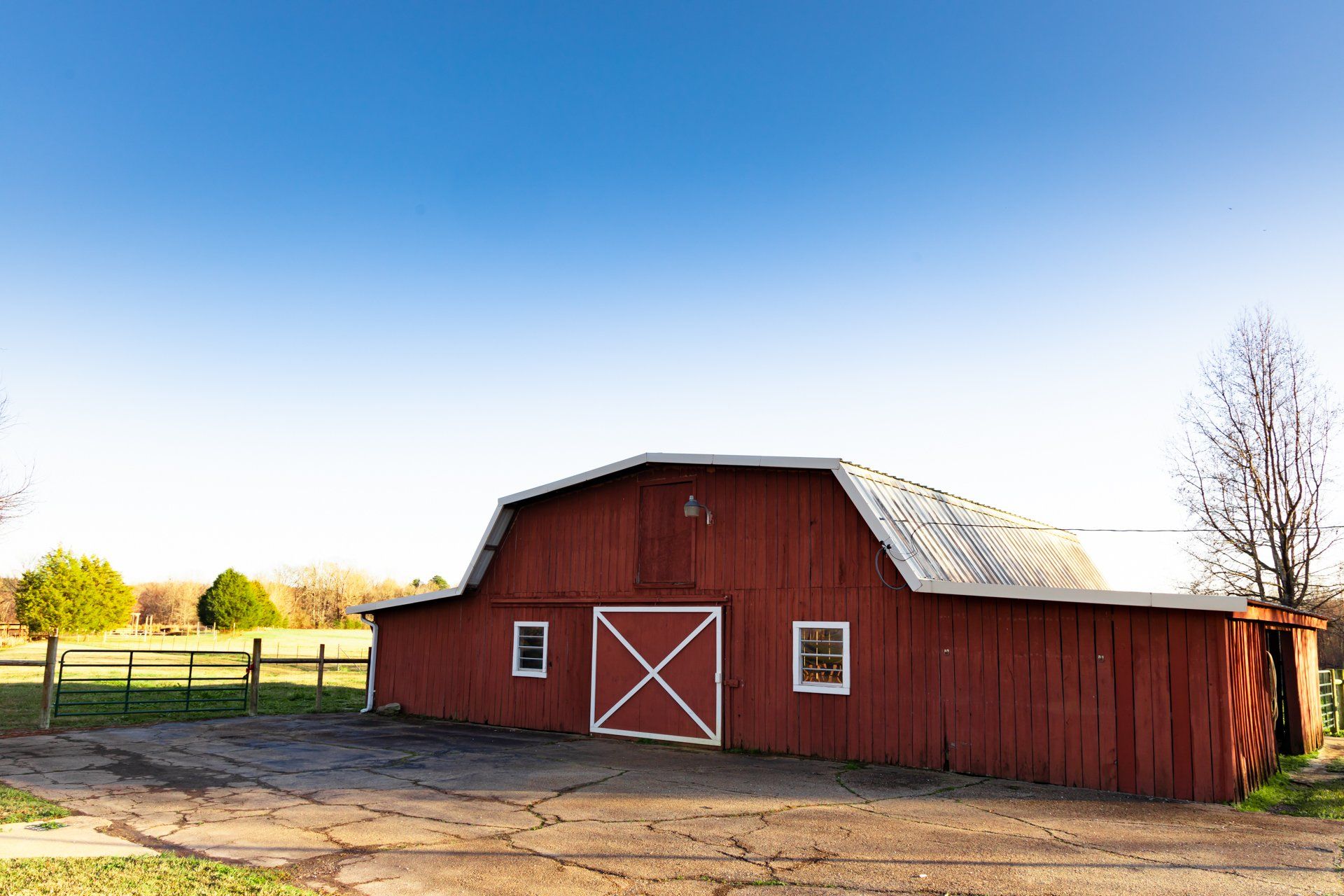 A red barn is sitting in the middle of a dirt field.