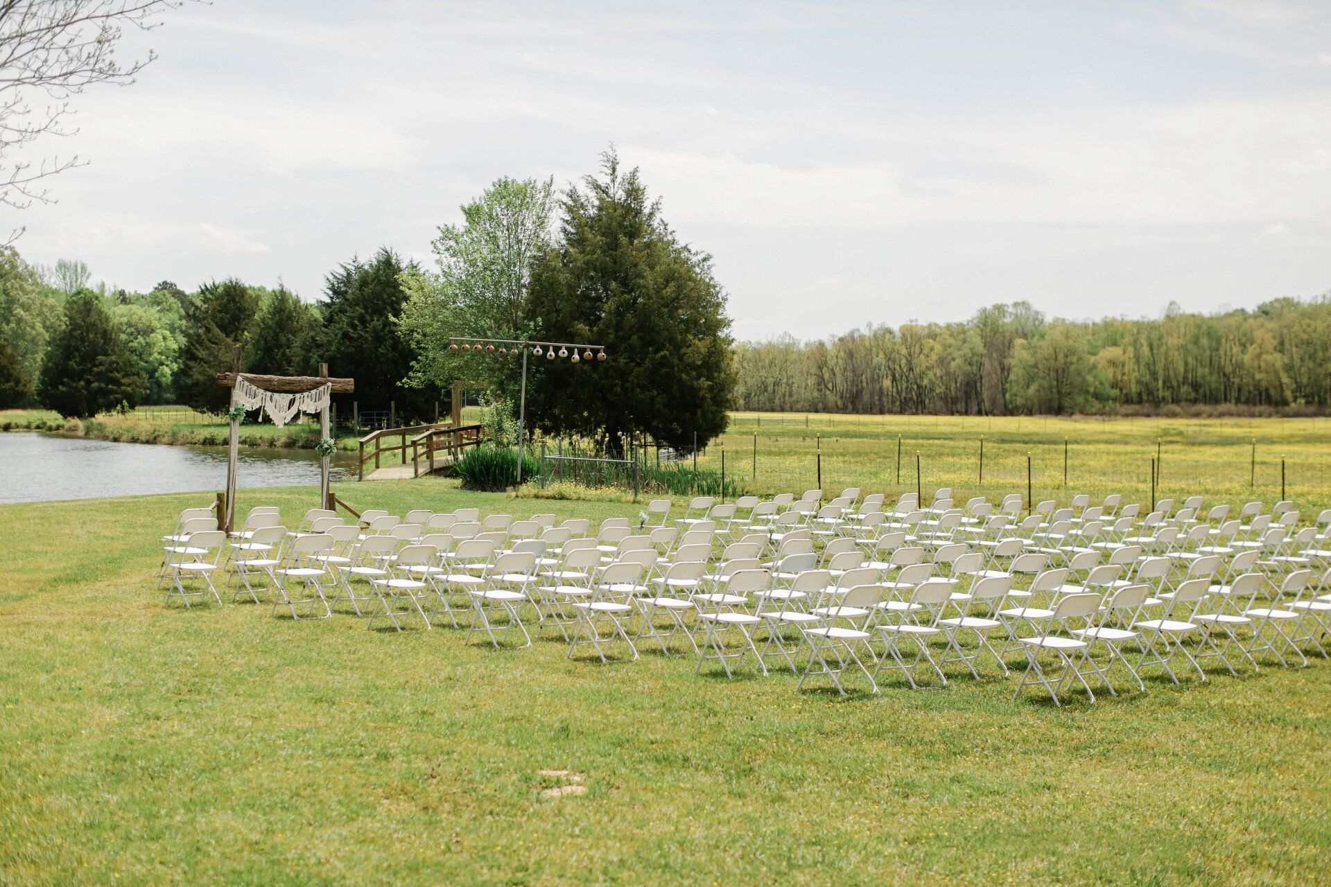 A row of white chairs are lined up in a grassy field.