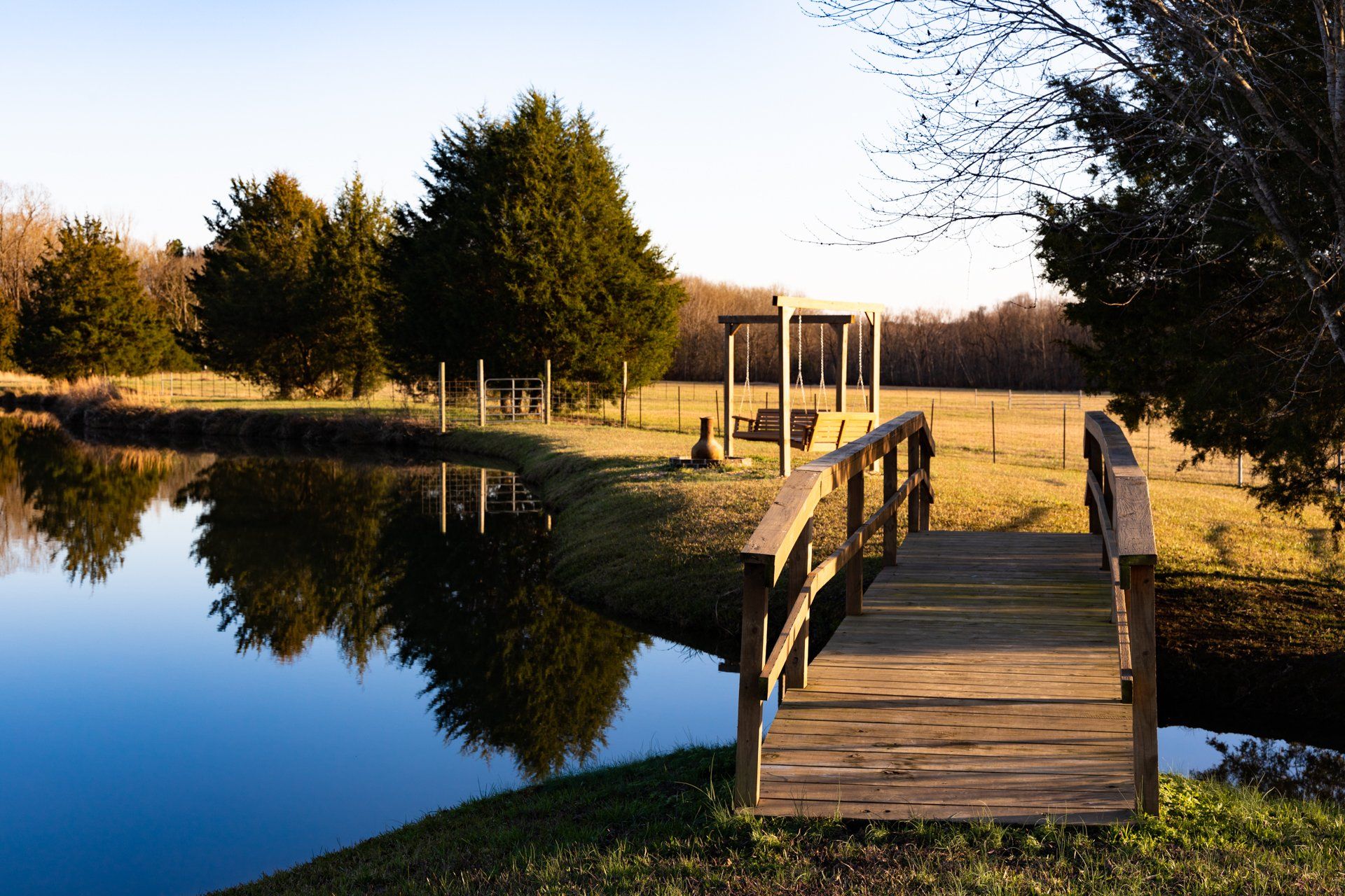 A wooden bridge over a body of water with trees in the background