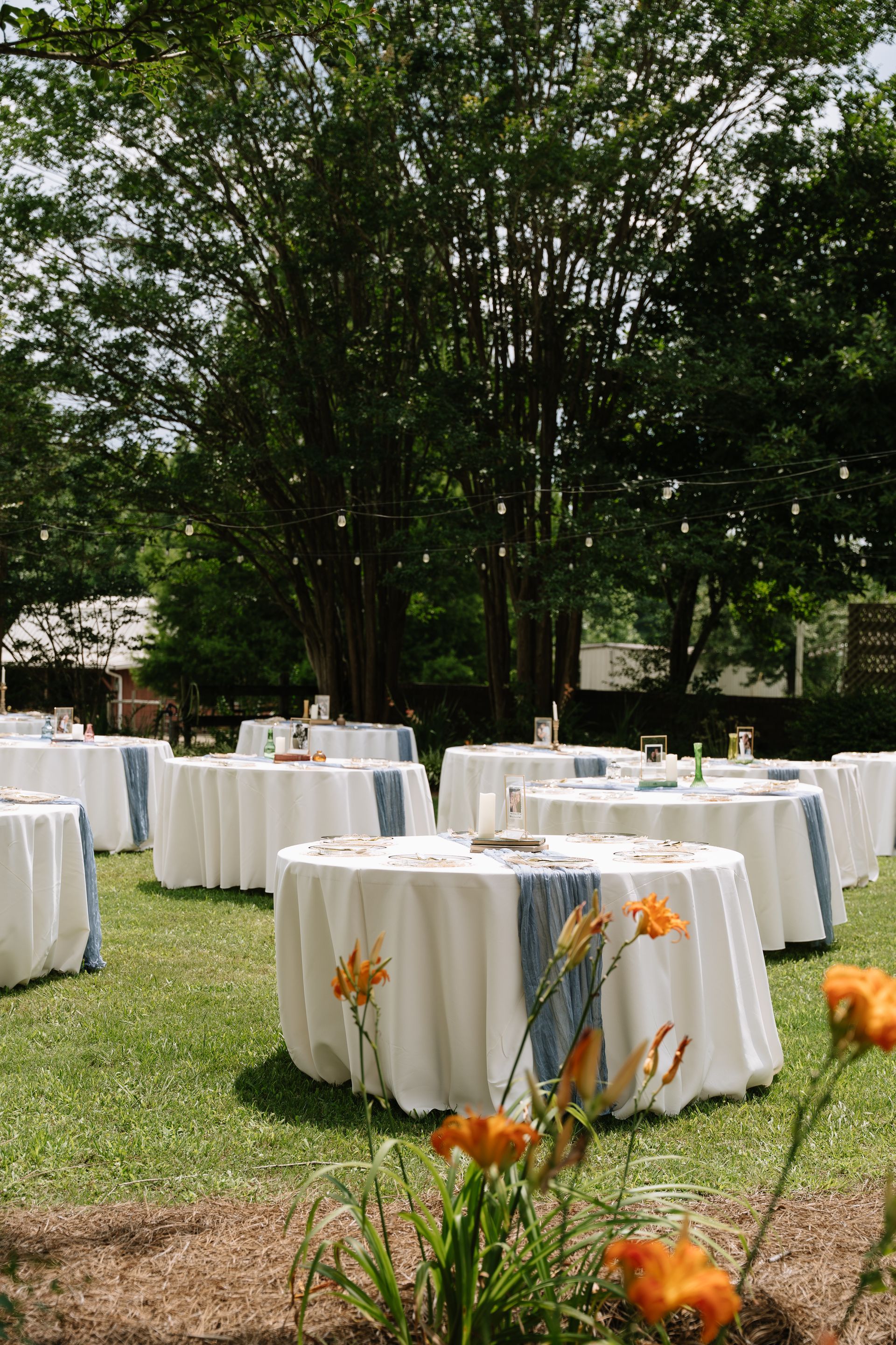 Tables set up with tableclothes and vases in a reception area with flowers around