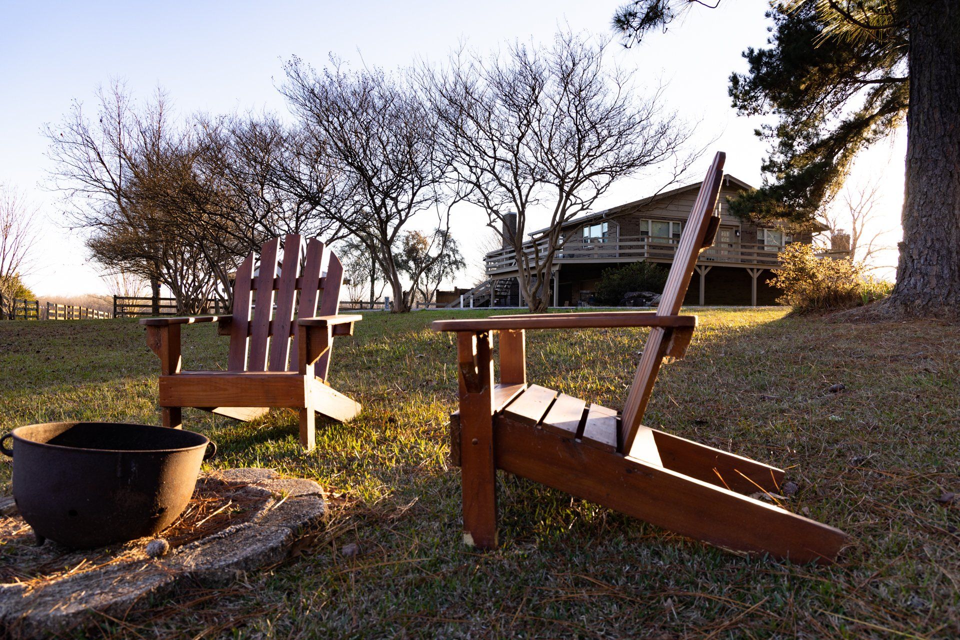 Two wooden chairs are sitting next to a fire pit in front of a house.