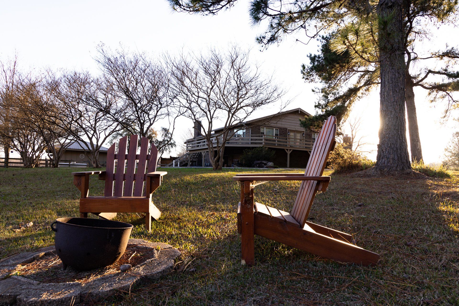 Two wooden chairs are sitting next to a fire pit in front of a house.