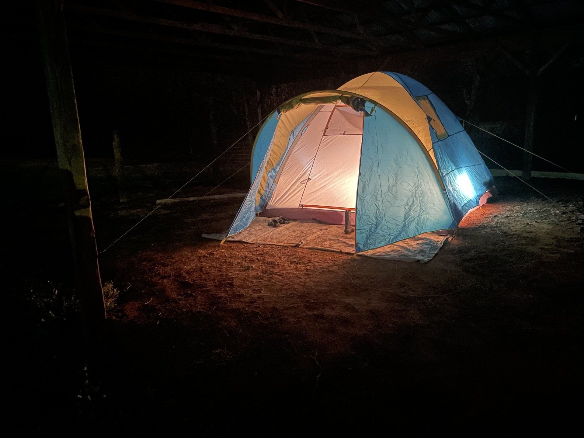 A blue and yellow tent is lit up at night.